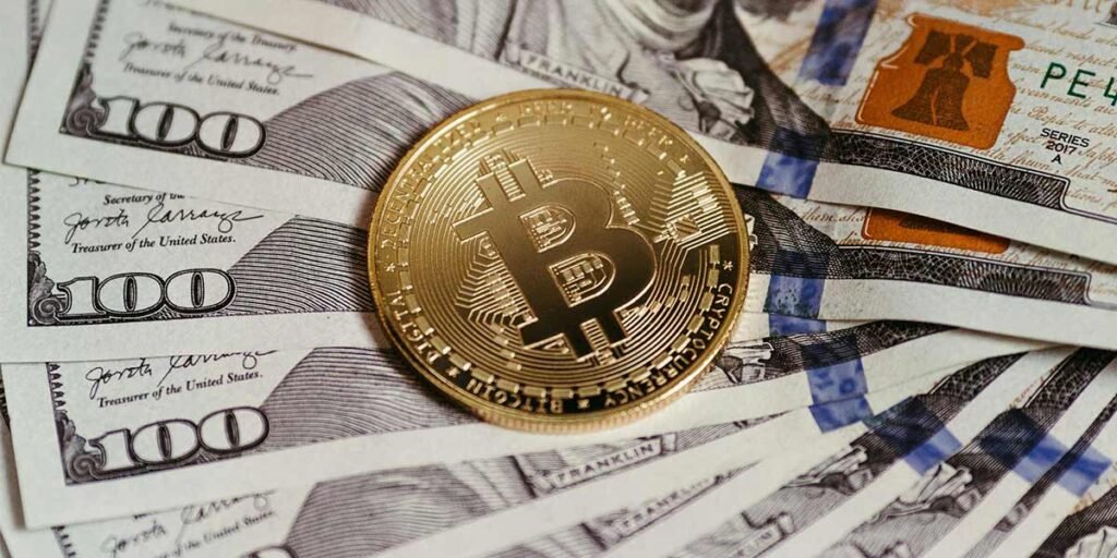 Dolares estadounidenses y una moneda de Bitcoin