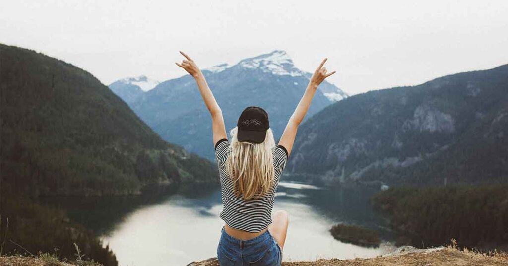 Mujer en la montaña con los brazos abierto representando la felicidad y libertad