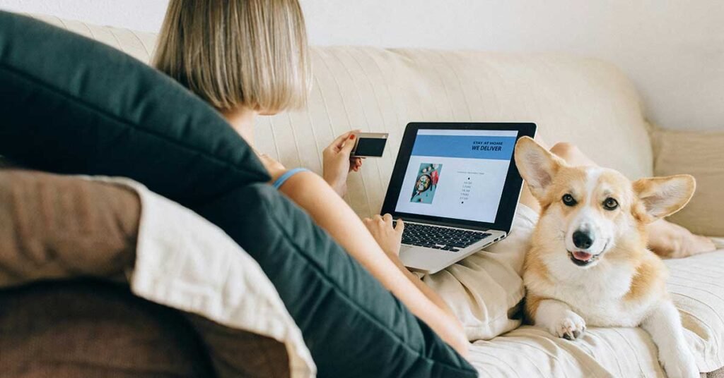 Mujer con su perro en el sofa haciendo compras online