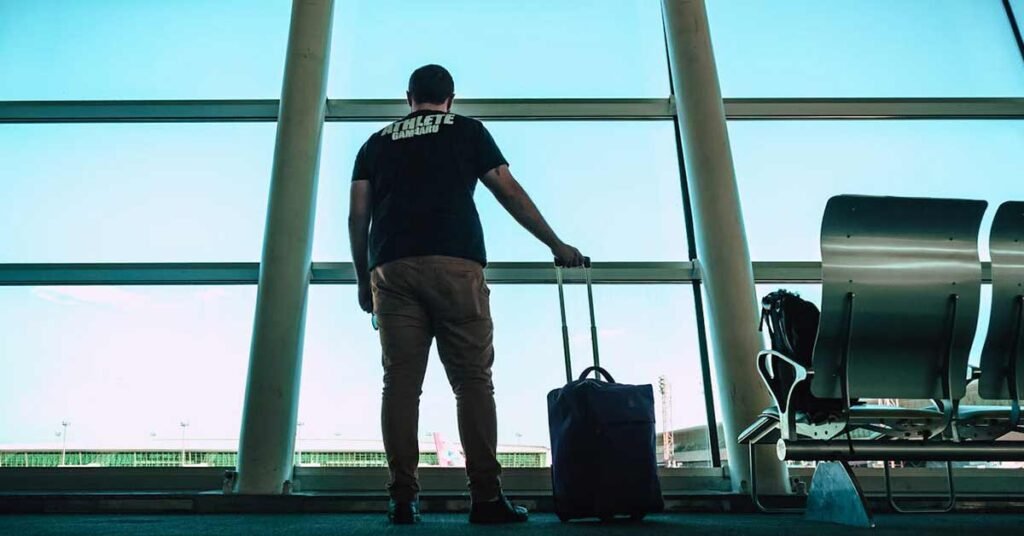 Hombre en el aeropuerto con equipaje en la mano esperando el avión